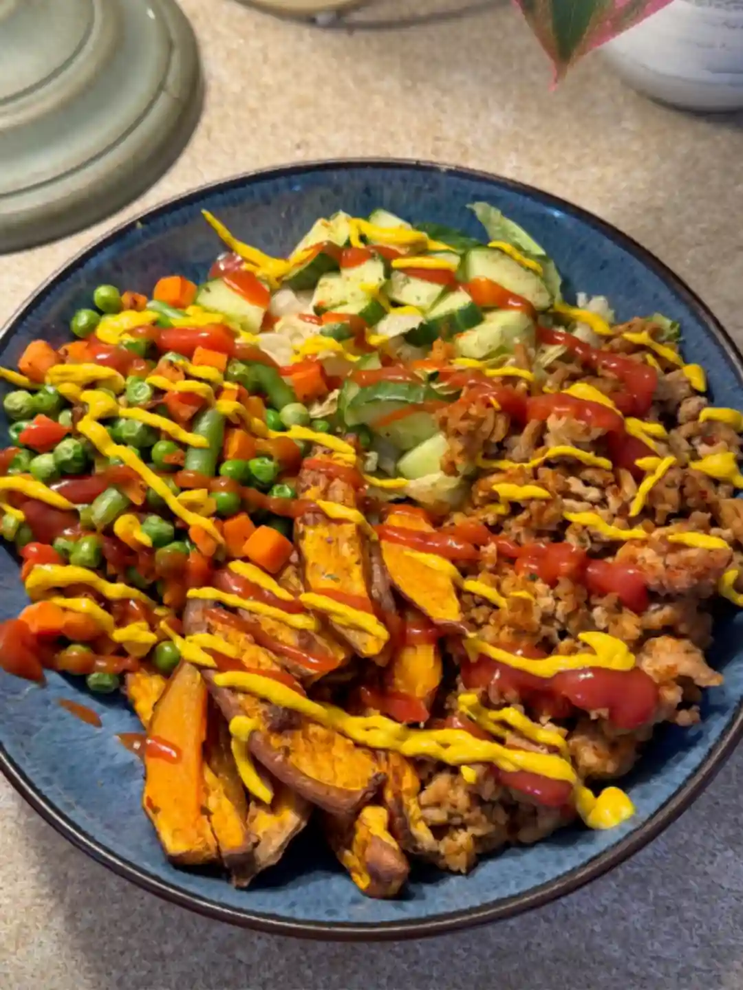 A bowl of mince, sweet potato wedges and mixed vegetables with mustard and hot sauce